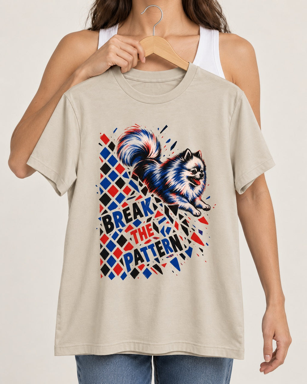 Pomeranian Break the Pattern T-Shirt in Sand, held up on a hanger