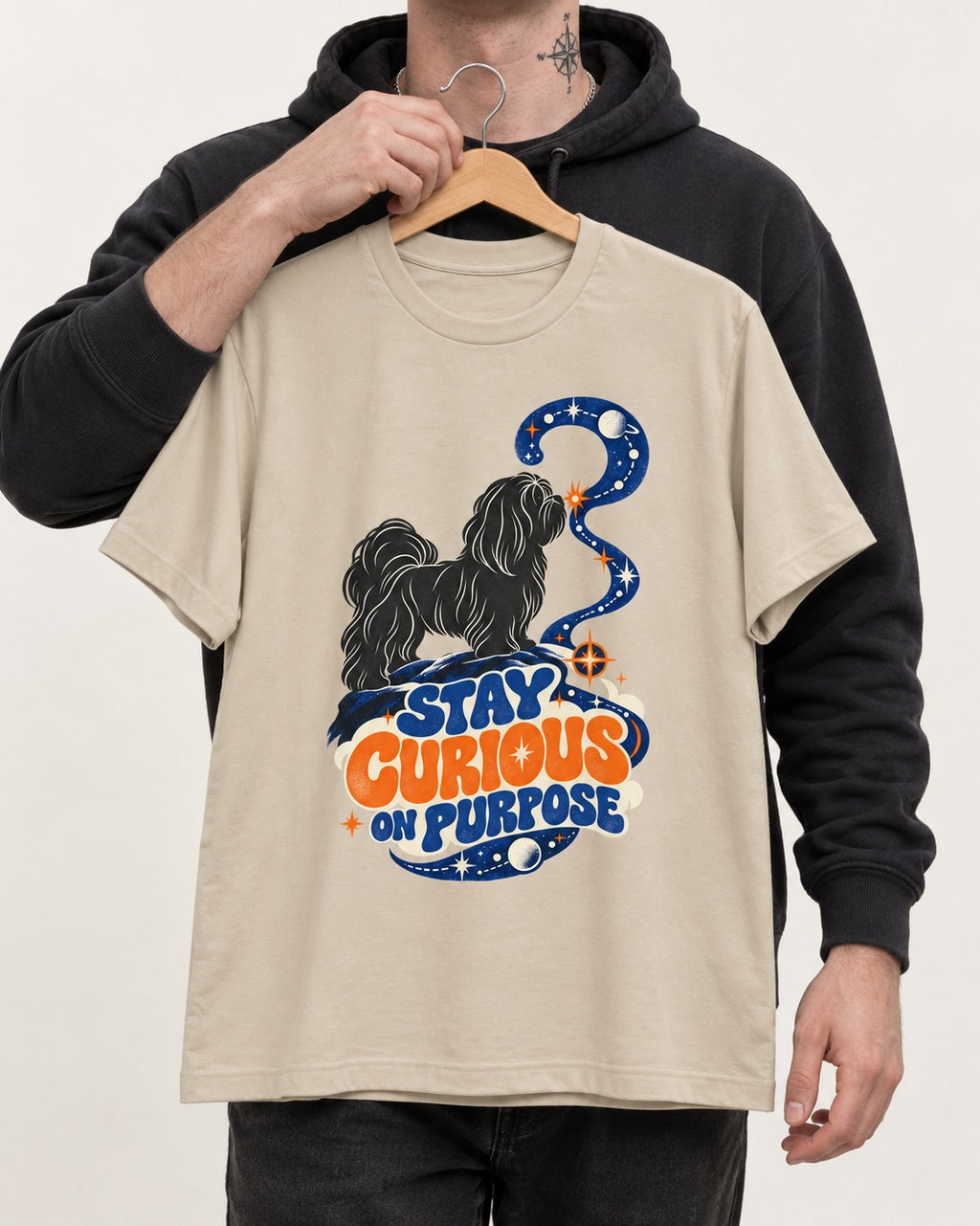 Stay Curious on Purpose Shih Tzu T-Shirt in Sand, held up on a hanger