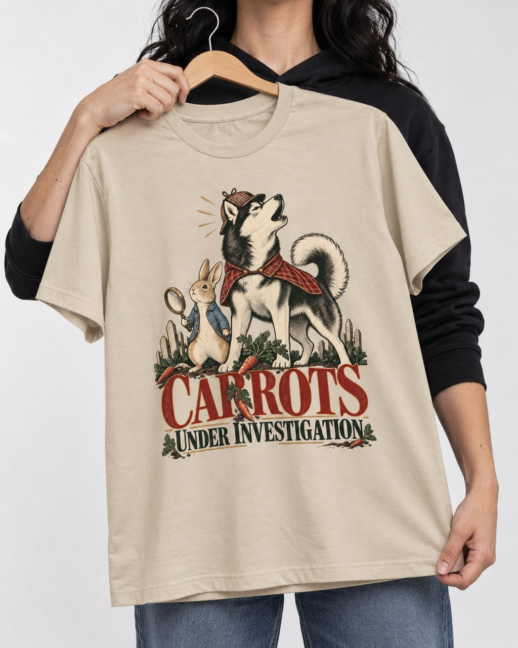 Carrots Under Husky Investigation T-Shirt in Sand, held up on a hanger