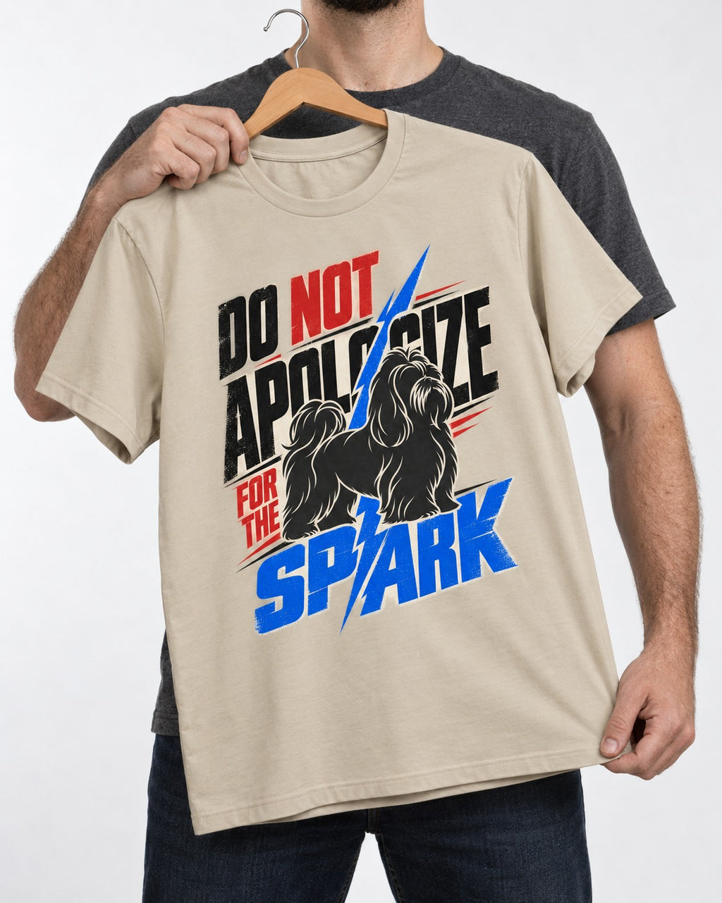 Never Apologize for Shih Tzu Spark T-Shirt in Sand, held up on a hanger