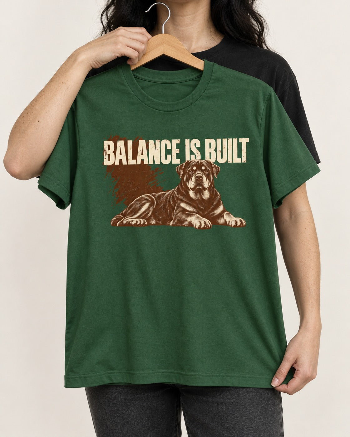 Rottweiler Balance Is Built Resting Strength Graphic T-Shirt in Forest Green, held up on a hanger