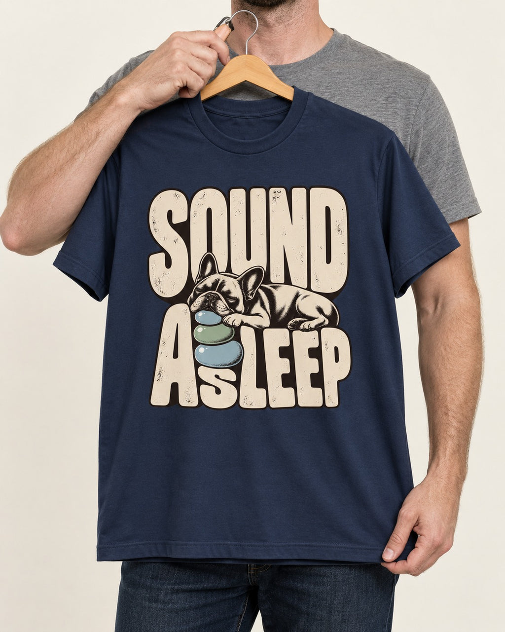 Frenchie Sound Asleep Stone Pillow Graphic T-Shirt in Navy, held up on a hanger