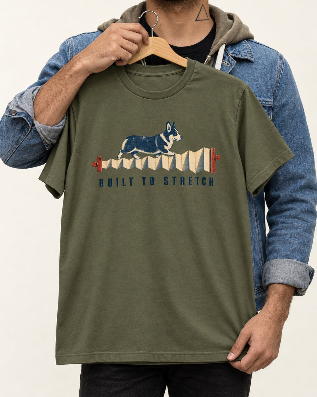 Corgi Built to Stretch Accordion Graphic T-Shirt in Heather Military Green, held up on a hanger
