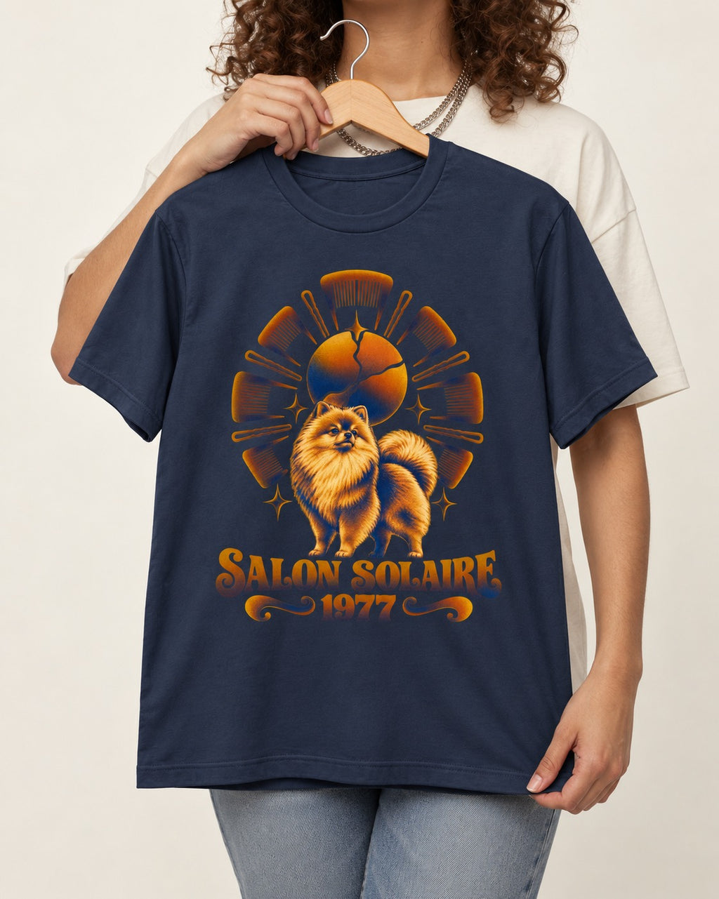 Pomeranian Salon Solaire 1977 Hairbrush Halo Graphic T-Shirt in Navy, held up on a hanger