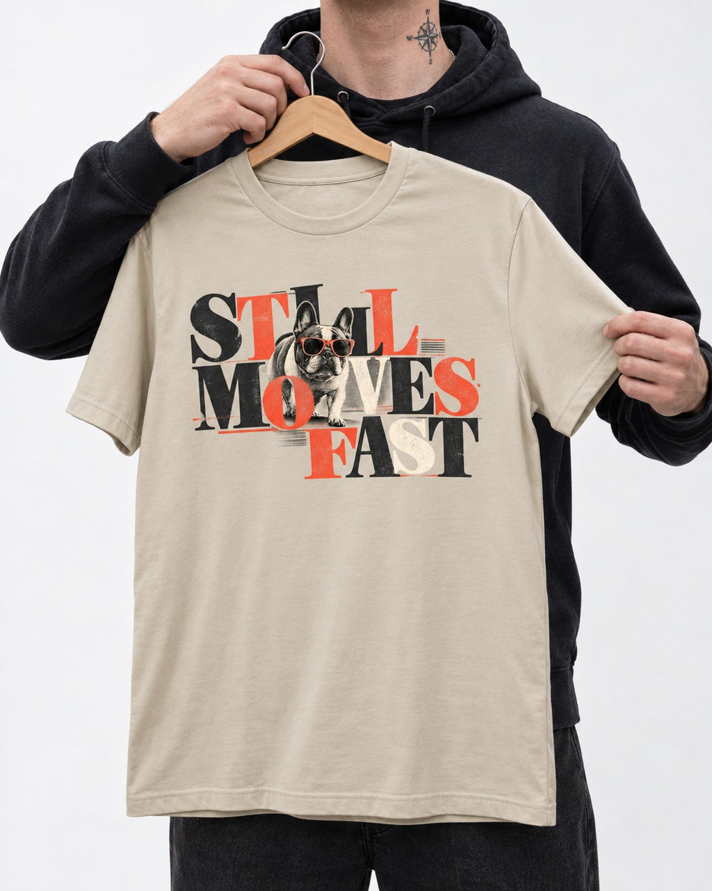 Frenchie Still Moves Fast T-Shirt in Sand, held up on a hanger