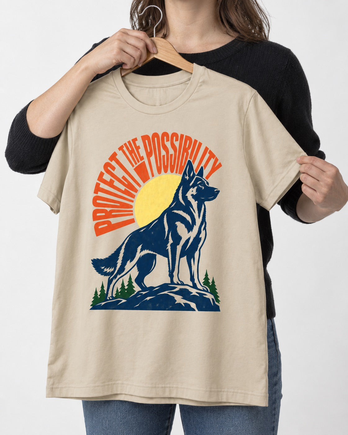 German Shepherd Dog Protect the Possibility T-Shirt in Sand, held up on a hanger