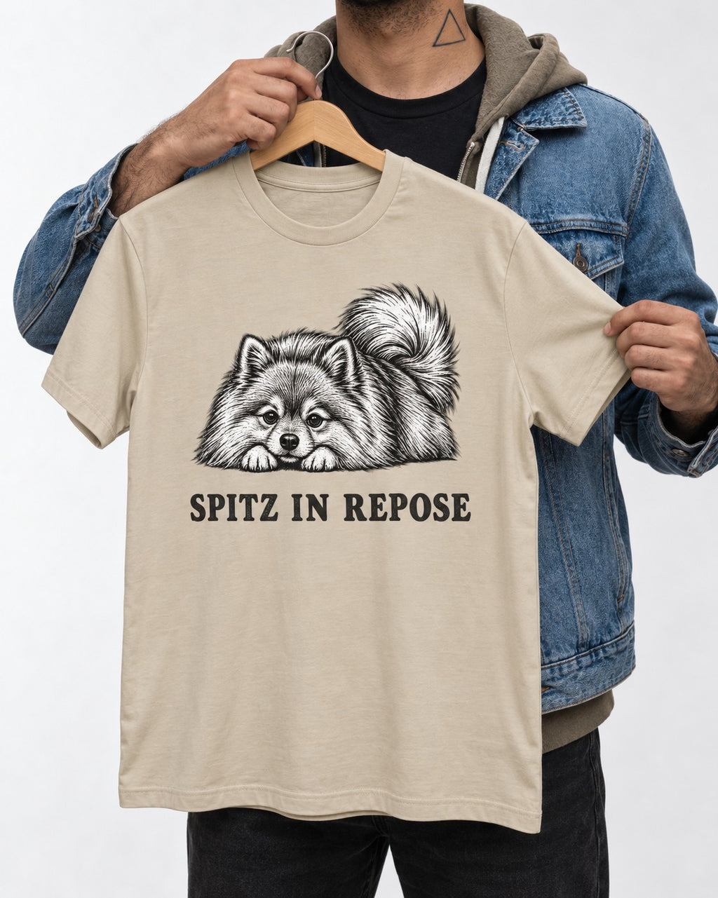 Pomeranian In Repose T-Shirt in Sand, held up on a hanger