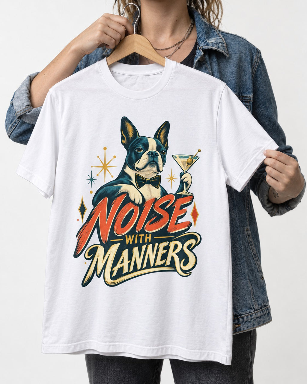 Boston Terrier Noise With Manners Cocktail Graphic T-Shirt in White, held up on a hanger