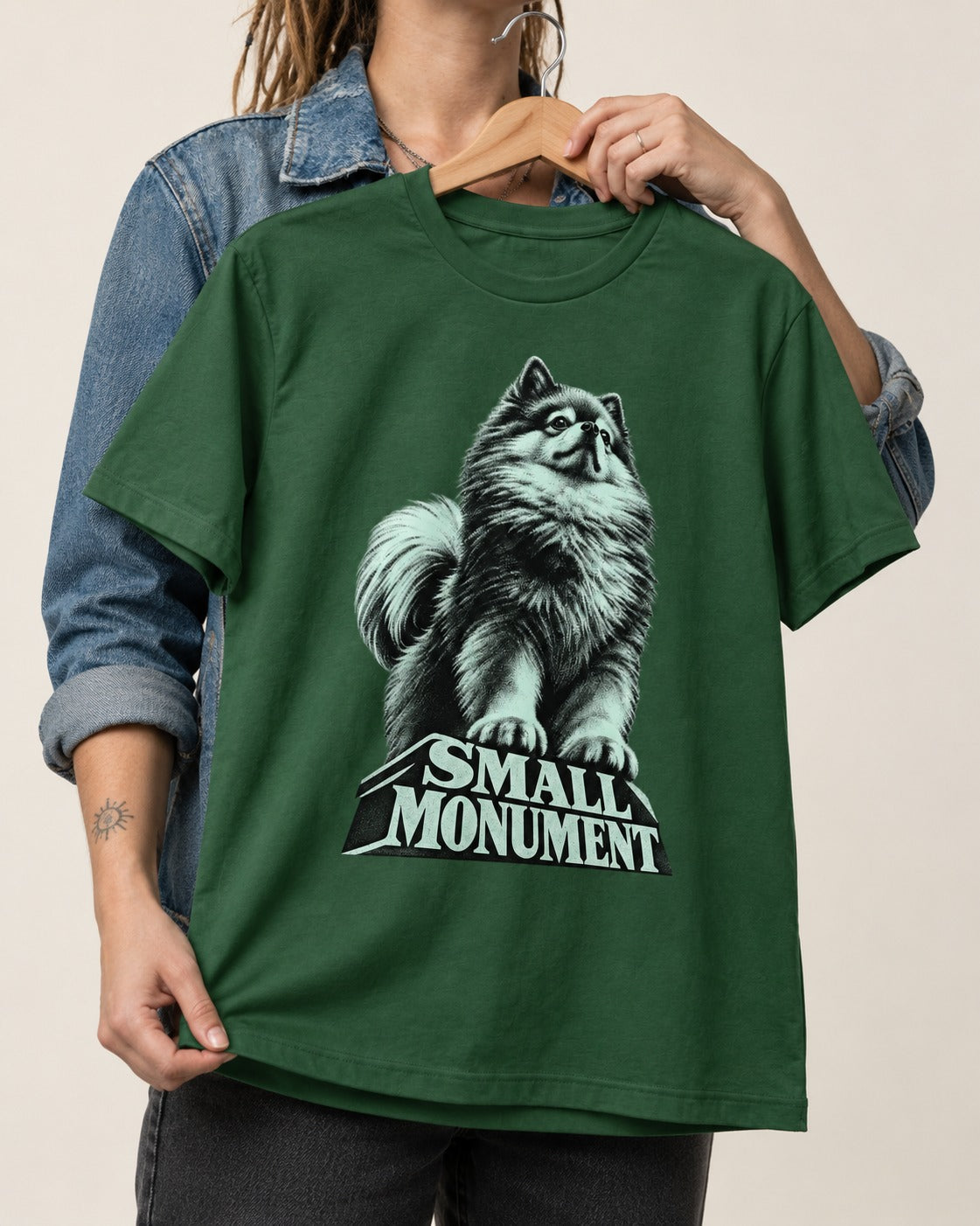 Pomeranian Small Monument Pedestal Graphic T-Shirt in Forest Green, held up on a hanger