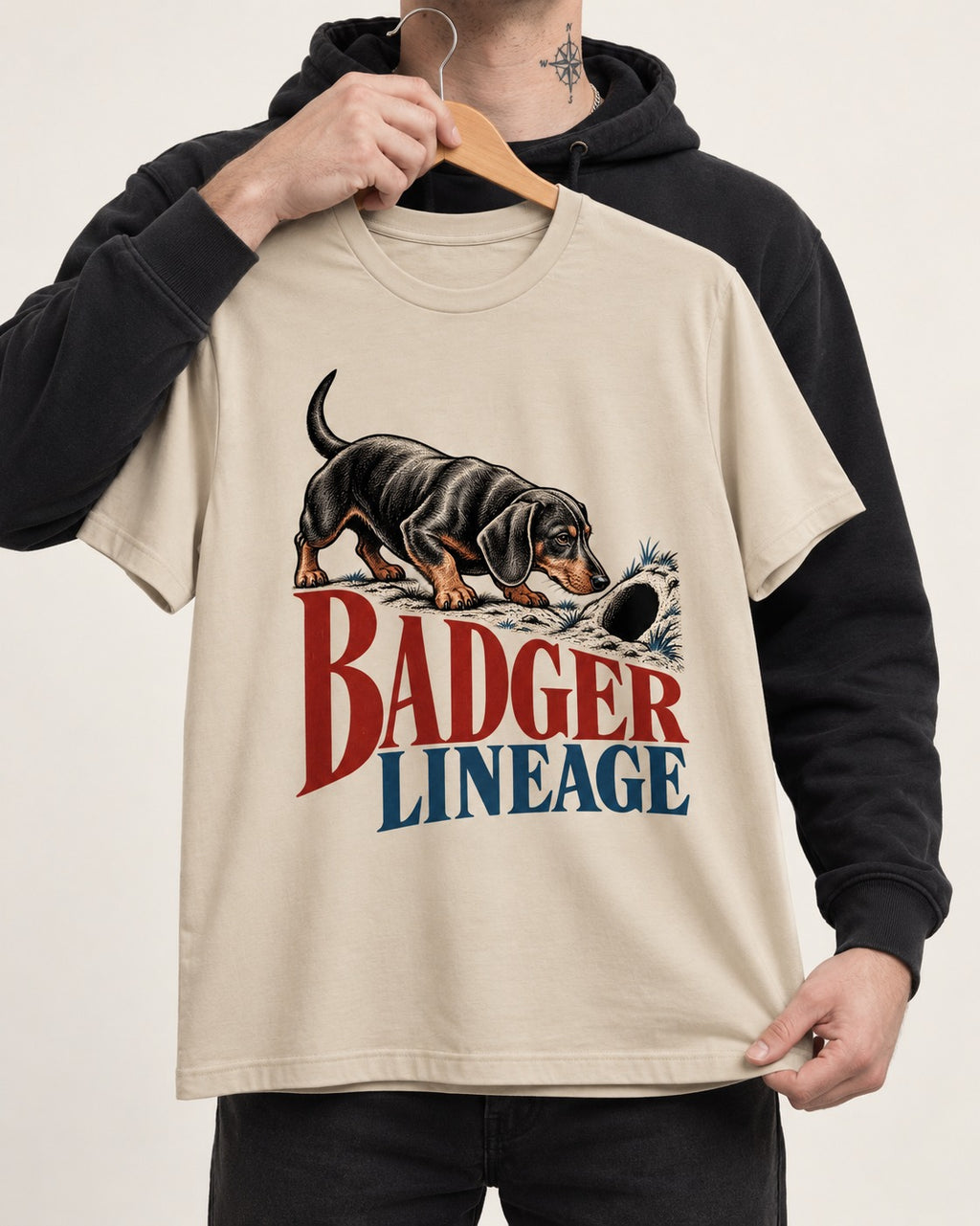 Dachshund Badger Lineage T-Shirt in Sand, held up on a hanger