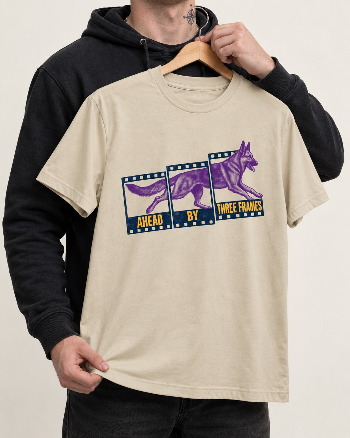 German Shepherd Dog Ahead by Three Frames T-Shirt in Sand, held up on a hanger