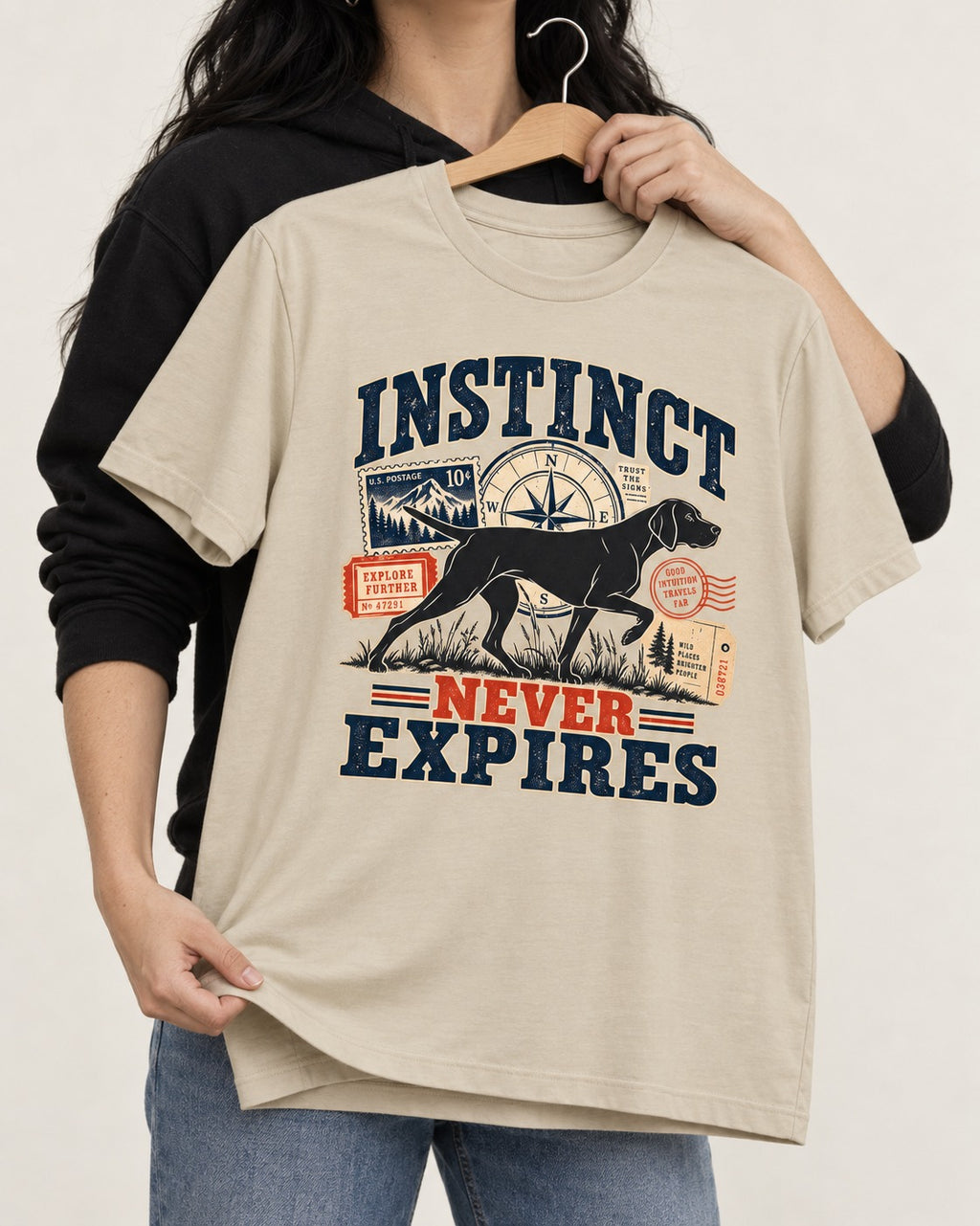German Shorthaired Pointer Instinct Never Expires T-Shirt in Sand, held up on a hanger