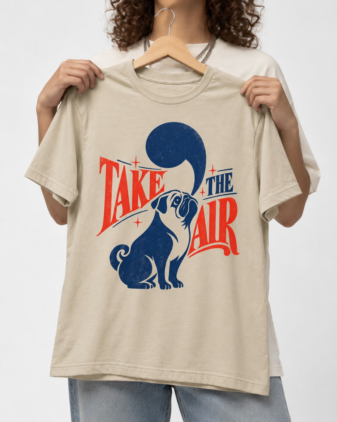 Pug Take the Air T-Shirt in Sand, held up on a hanger