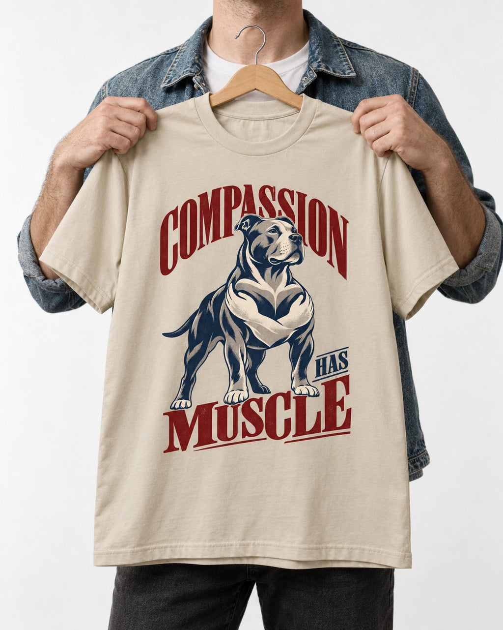 Pitbull Compassion Has Muscle T-Shirt in Sand, held up on a hanger