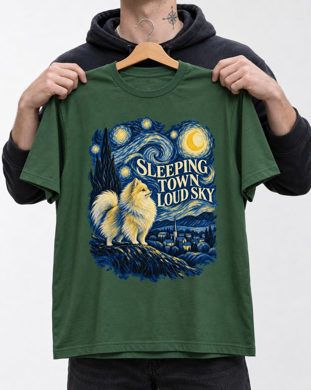 Pomeranian Sleeping Town Loud Sky Starry Night Graphic T-Shirt in Forest Green, held up on a hanger