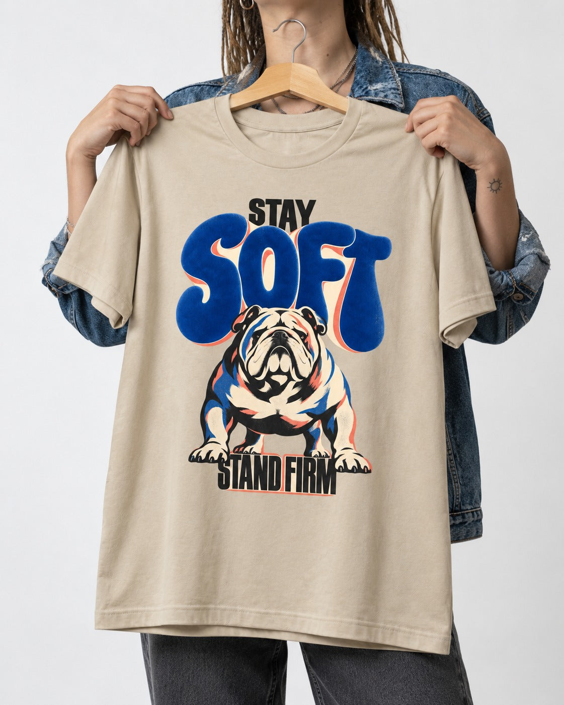 Stay Soft Stand Firm English Bulldog T-Shirt in Sand, held up on a hanger