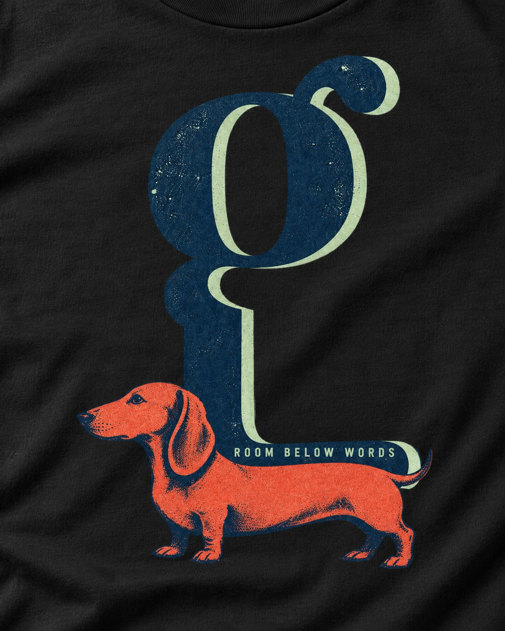 Dachshund Room Below Words Lowercase G Graphic T-Shirt in Black, close-up of the graphic