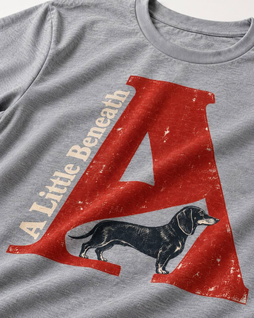Dachshund A Little Beneath Monumental Letter Graphic T-Shirt in Sport Grey, close-up of the graphic