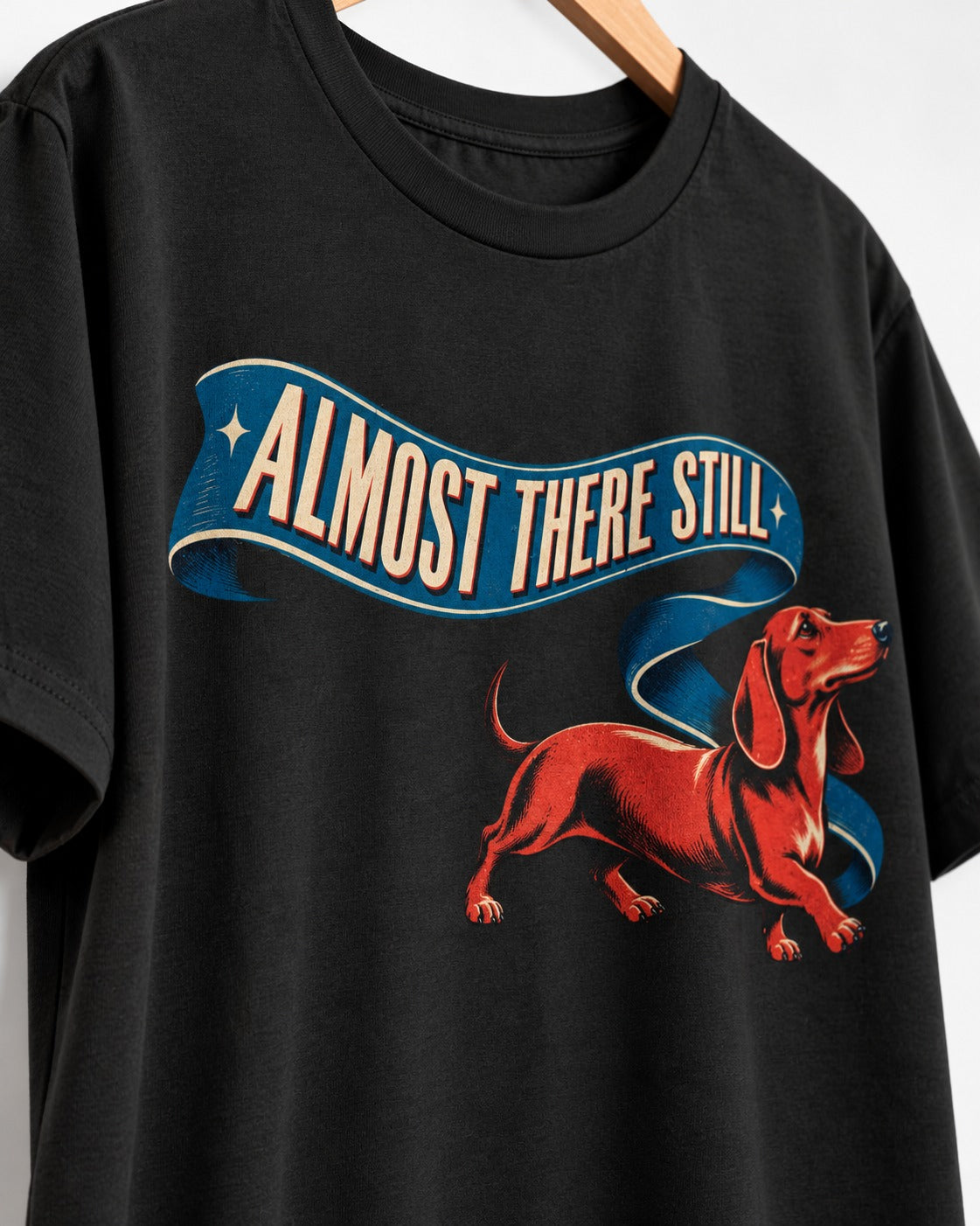 Dachshund Almost There Still Ribbon Graphic T-Shirt in Black, close-up of the graphic