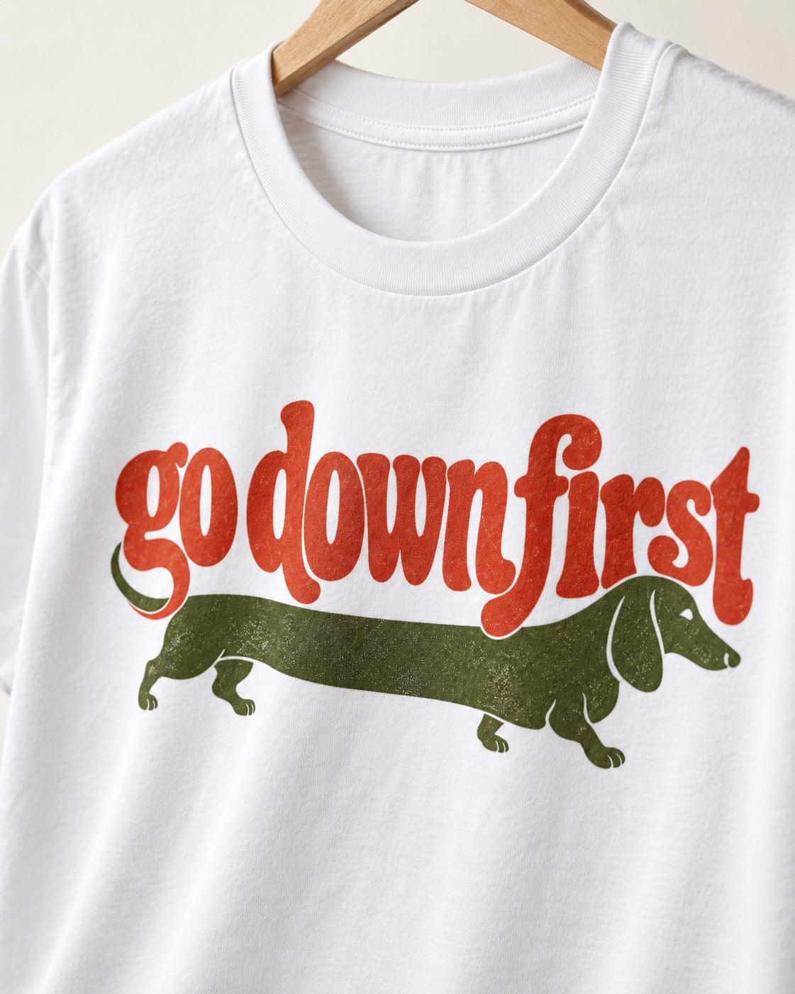 Dachshund Goes Down First T-Shirt in White, close-up of the graphic