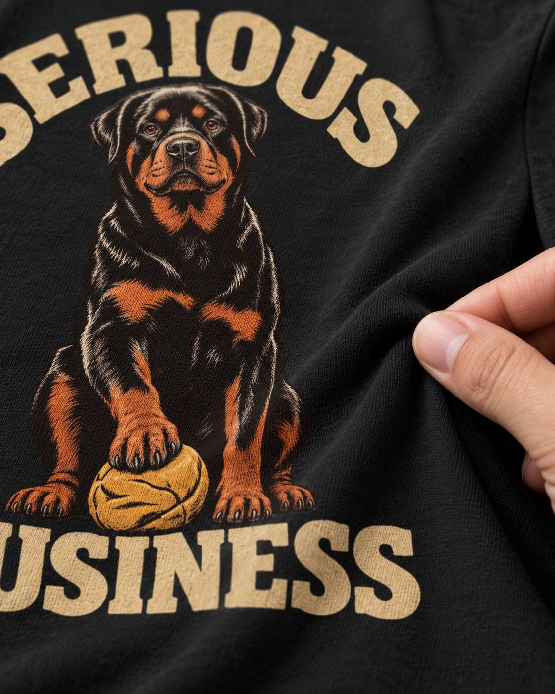 Rottweiler Serious Business Ball Under Paw Graphic T-Shirt in Black, close-up of the graphic