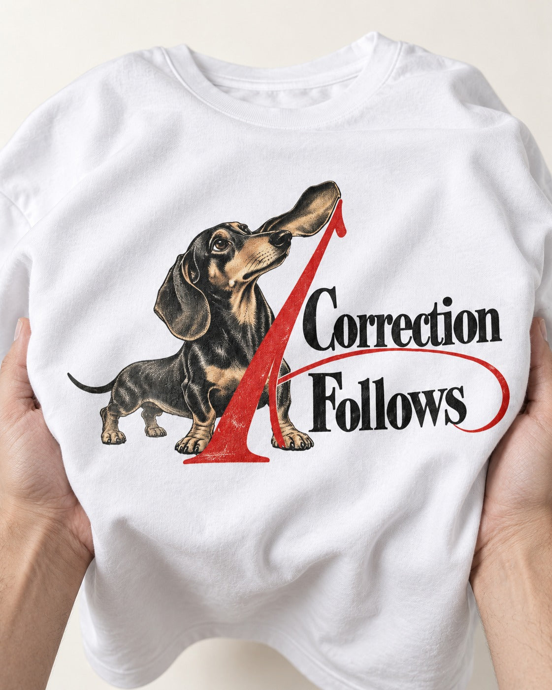 A Dachshund Correction Follows T-Shirt in White, close-up of the graphic