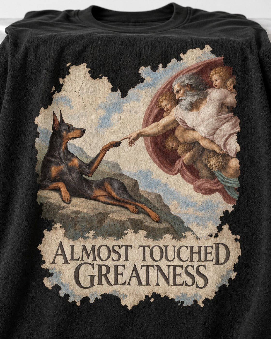 Doberman Almost Touched Greatness Creation Scene Graphic T-Shirt in Black, close-up of the graphic