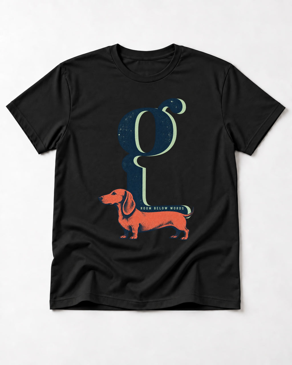 Dachshund Room Below Words Lowercase G Graphic T-Shirt in Black, flat lay product photo