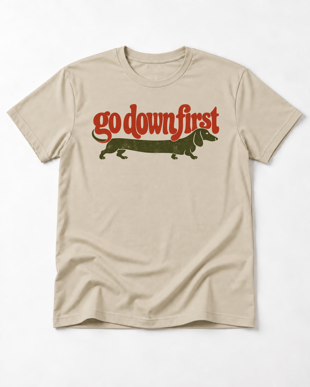 Dachshund Goes Down First T-Shirt in Sand, flat lay product photo