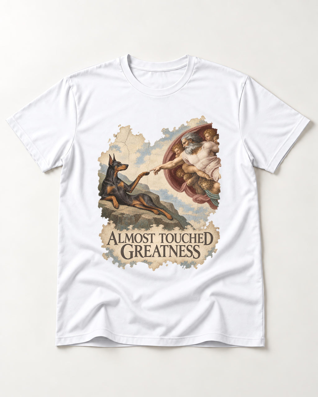Doberman Almost Touched Greatness Creation Scene Graphic T-Shirt in White, flat lay product photo