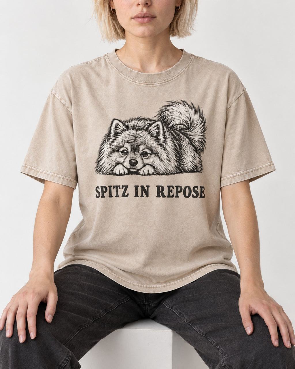 Pomeranian In Repose Washed Tee in Apricot, worn by a seated model