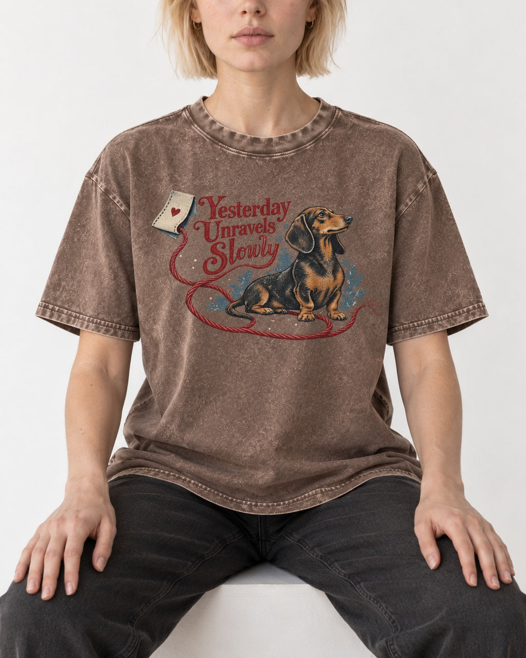 Yesterday Unravels Slowly with Dachshund Washed Tee in Coffee, worn by a seated model