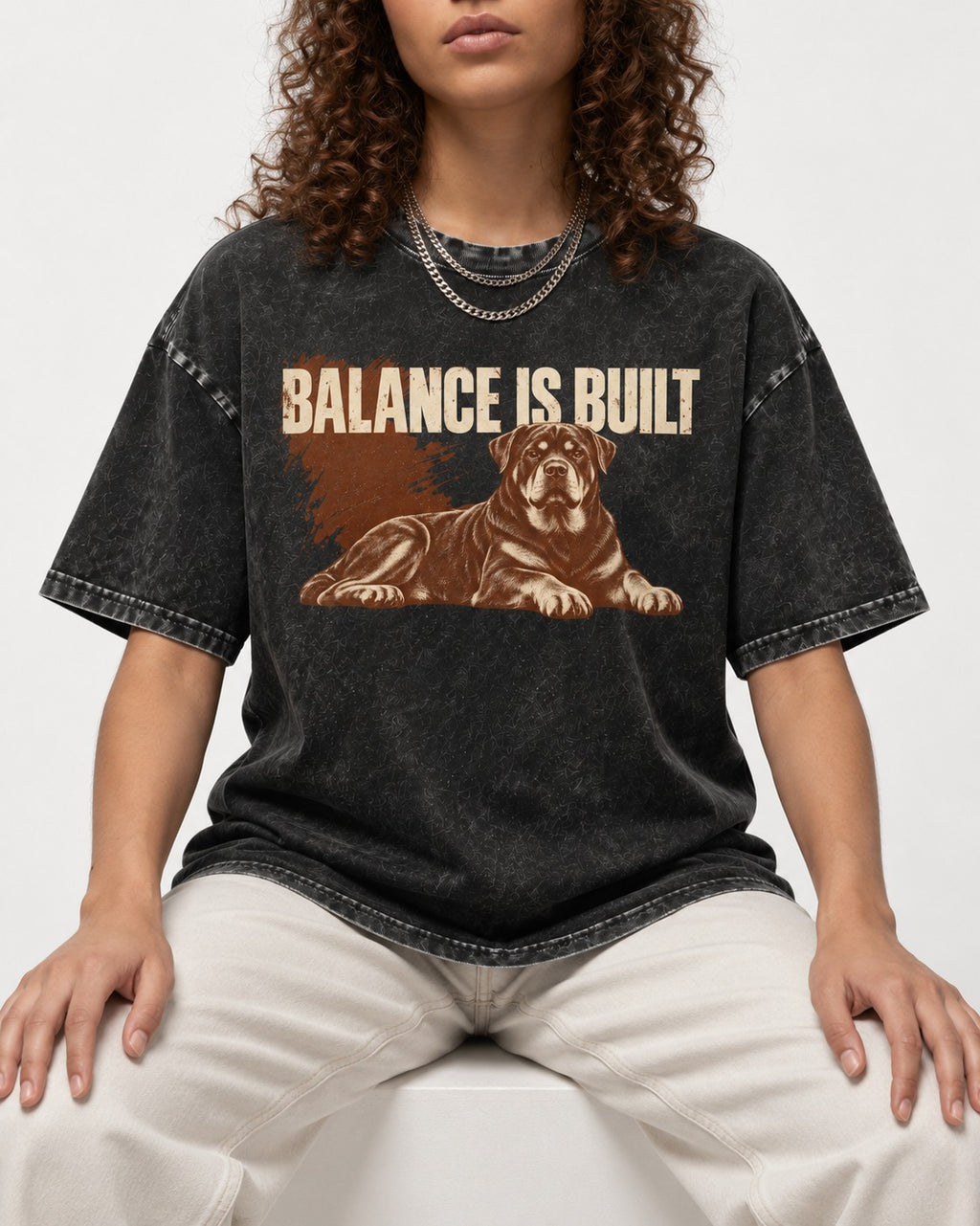 Rottweiler Balance Is Built Resting Strength Graphic Washed Tee in Black, worn by a seated model