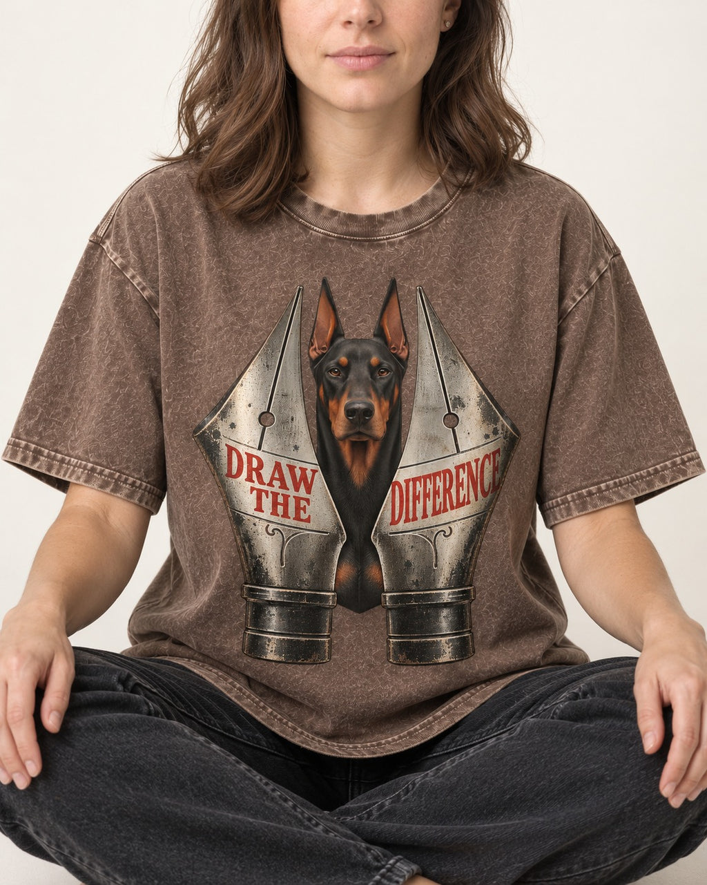 Doberman Draw the Difference Washed Tee in Coffee, worn by a seated model