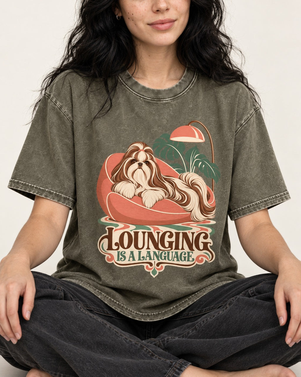 Shih Tzu Lounging Is a Language Retro Lounge Graphic Washed Tee in Army Green, worn by a seated model