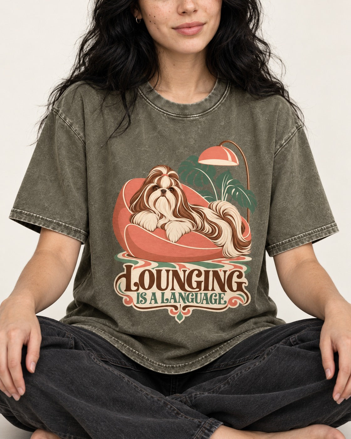 Shih Tzu Lounging Is a Language Retro Lounge Graphic Washed Tee in Army Green, worn by a seated model