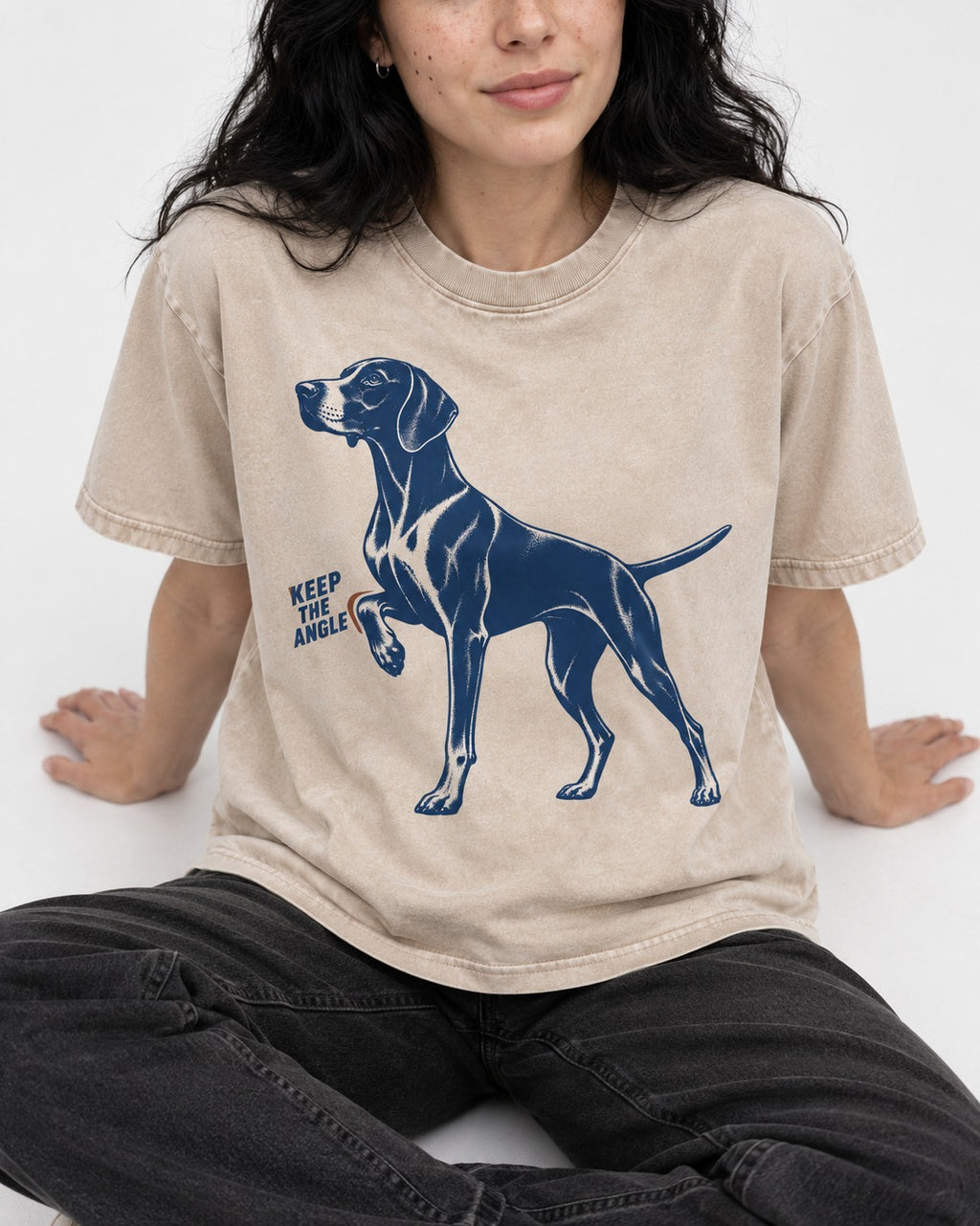 Keep the Angle German Shorthaired Pointer Washed Tee in Apricot, worn by a seated model