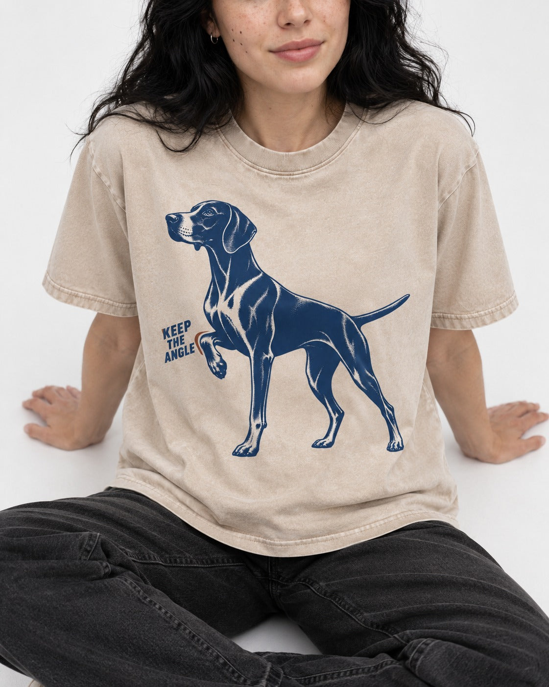Keep the Angle German Shorthaired Pointer Washed Tee in Apricot, worn by a seated model