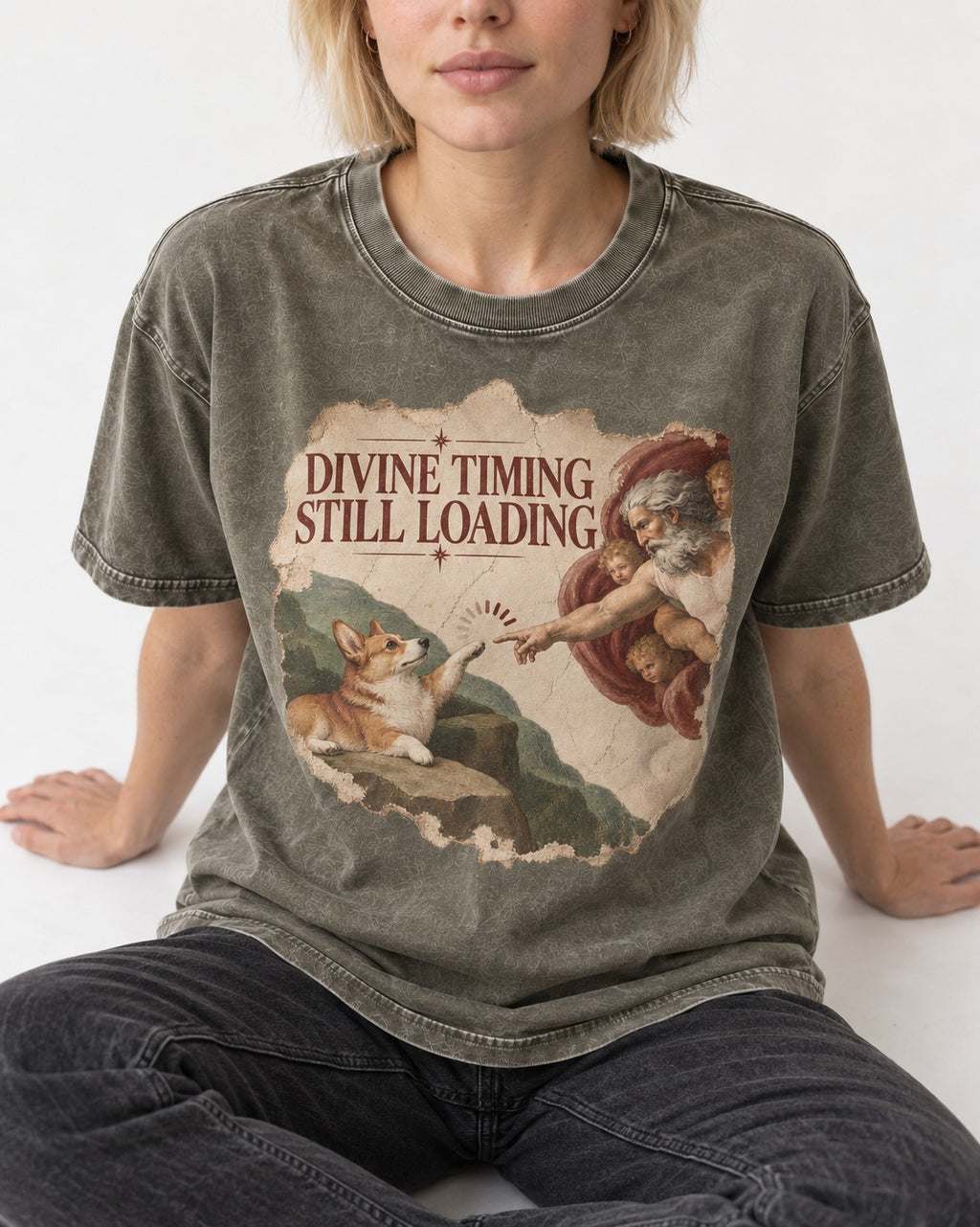 Corgi Divine Timing Still Loading Creation Parody Washed Tee in Army Green, worn by a seated model