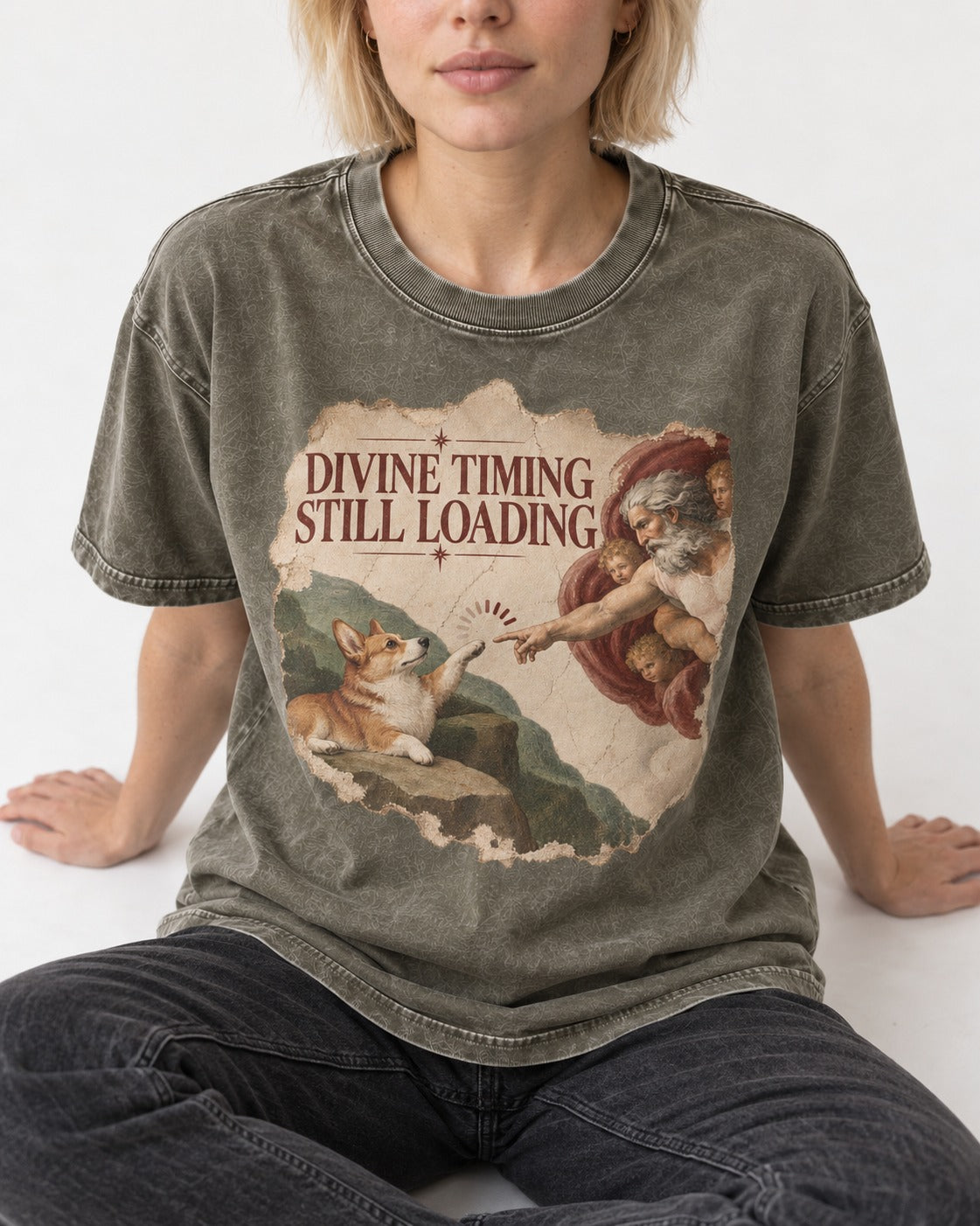 Corgi Divine Timing Still Loading Creation Parody Washed Tee in Army Green, worn by a seated model