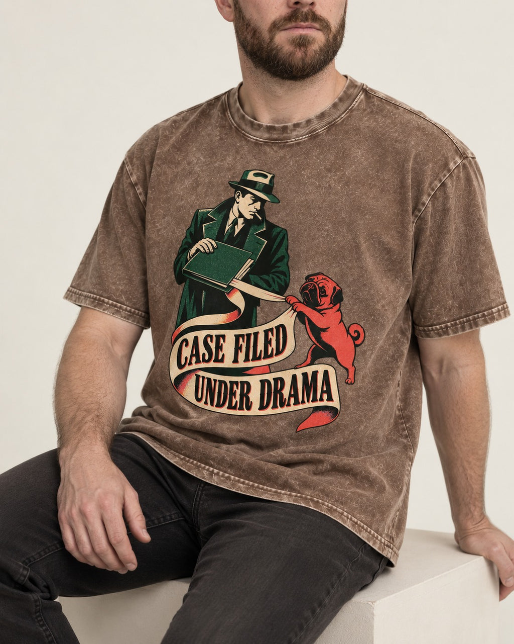 Pug Case Filed Under Drama Washed Tee in Coffee, worn by a seated model