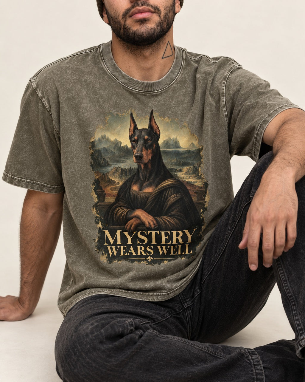 Doberman Mystery Wears Well Renaissance Portrait Graphic Washed Tee in Army Green, worn by a seated model