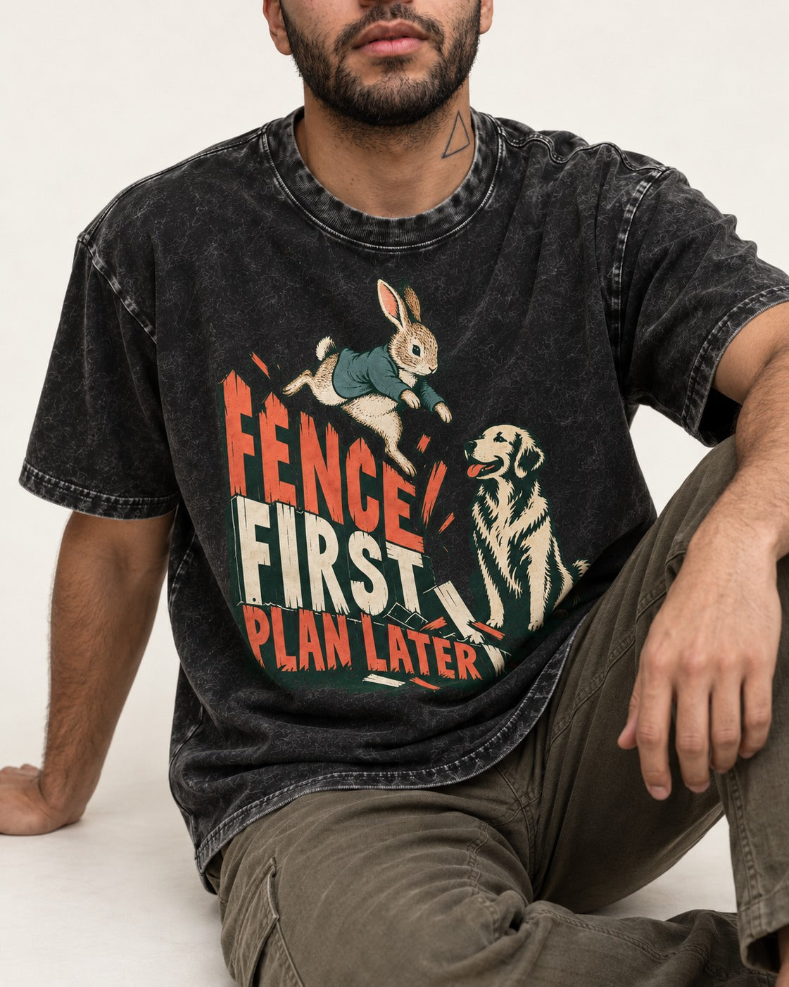 Golden Retriever Fence First Plan Later Rabbit Jump Graphic Washed Tee in Black, worn by a seated model
