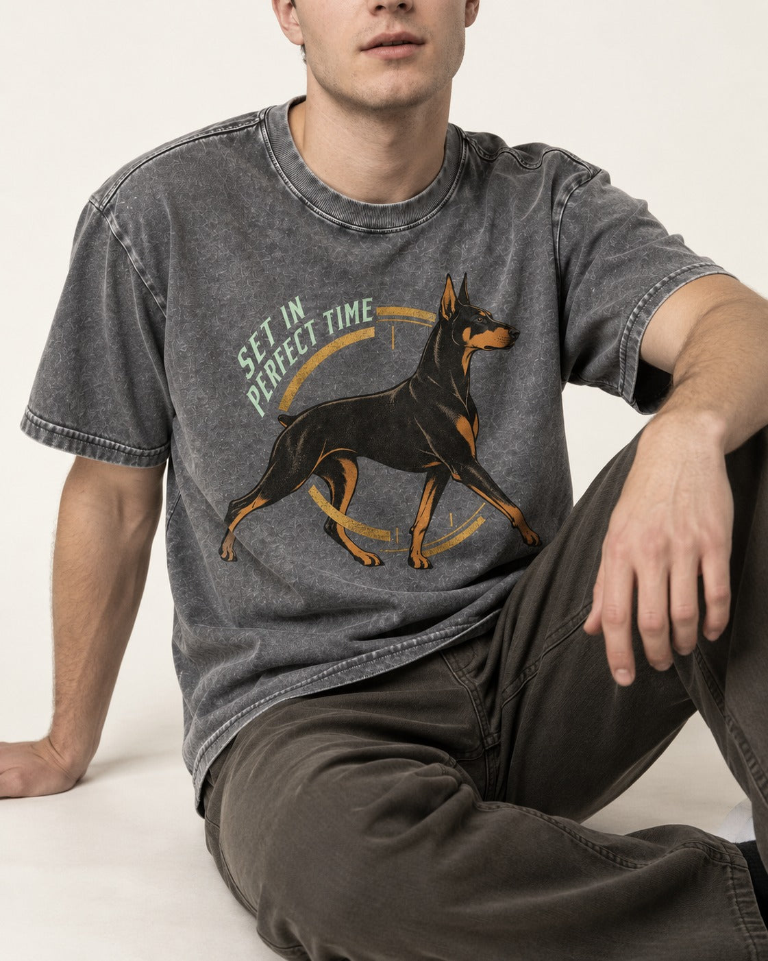 Doberman Set in Perfect Time Clock Stride Graphic Washed Tee in Gray, worn by a seated model