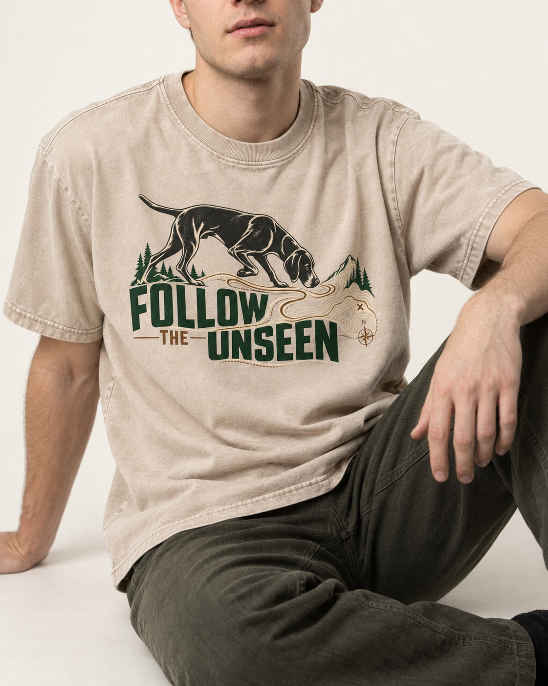 Follow the Unseen German Shorthaired Pointer Washed Tee in Apricot, worn by a seated model