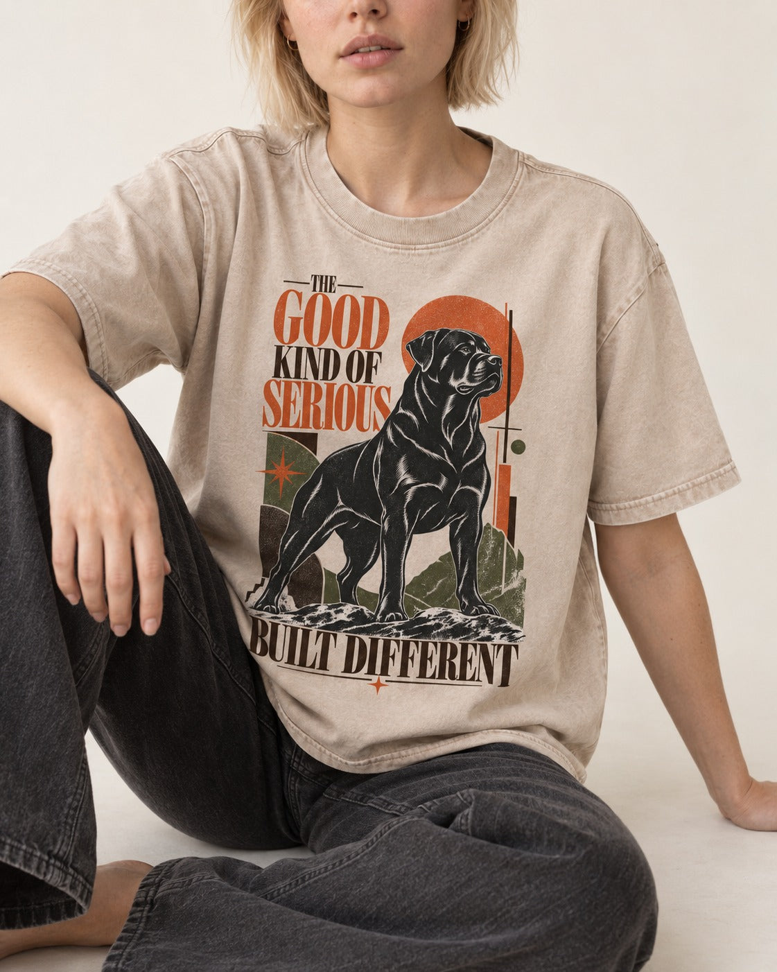 Rottweiler Built Different Washed Tee in Apricot, worn by a seated model