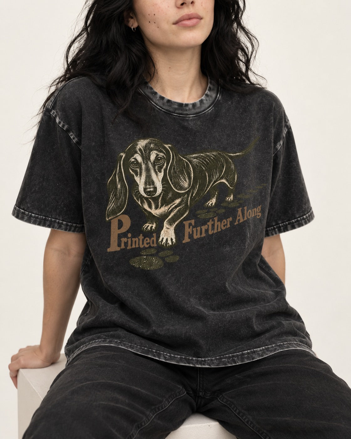 Dachshund Printed Further Along Footprint Graphic Washed Tee in Black, worn by a seated model