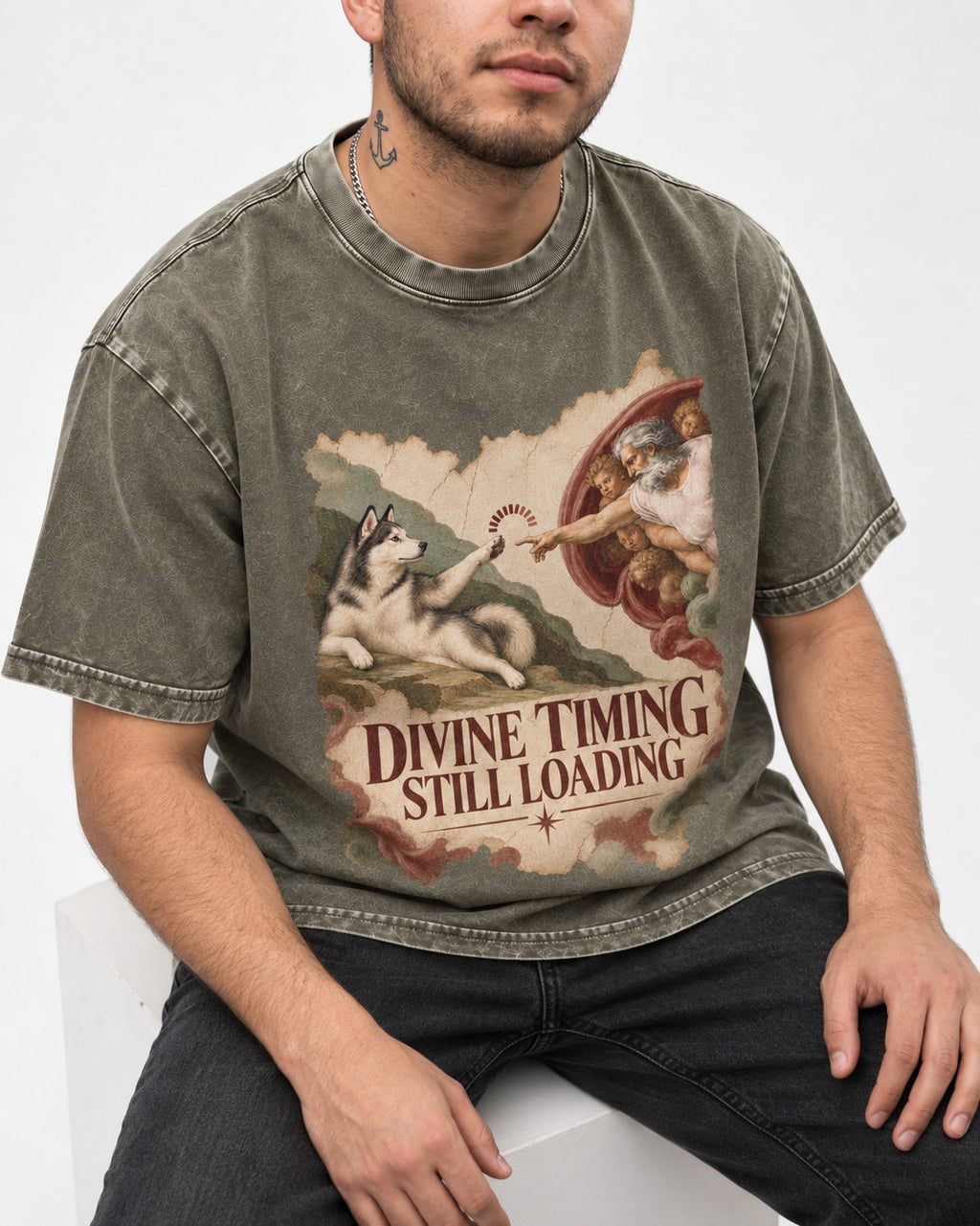 Husky Divine Timing Still Loading Creation Parody Graphic Washed Tee in Army Green, worn by a seated model