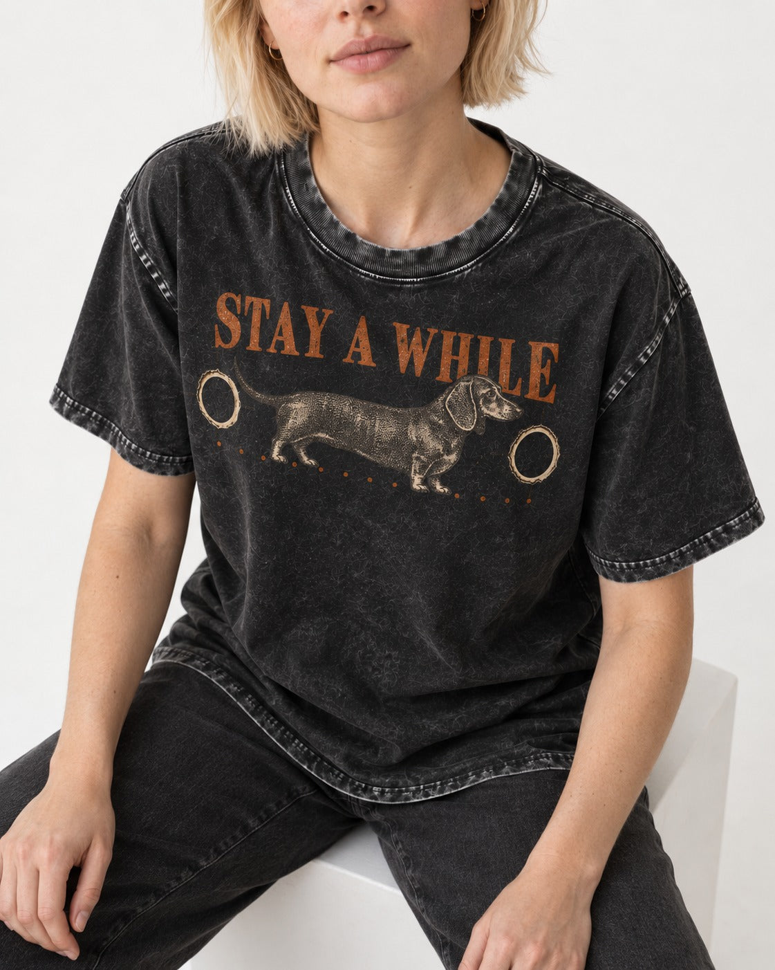 Dachshund Stay A While Ornamental Portrait Graphic Washed Tee in Black, worn by a seated model