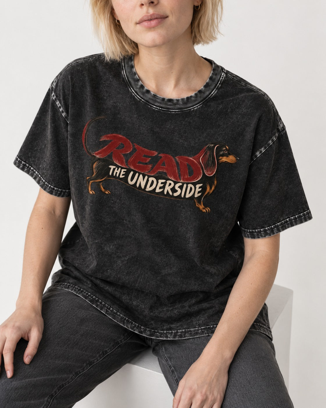 Dachshund Read The Underside Body Lettering Graphic Washed Tee in Black, worn by a seated model
